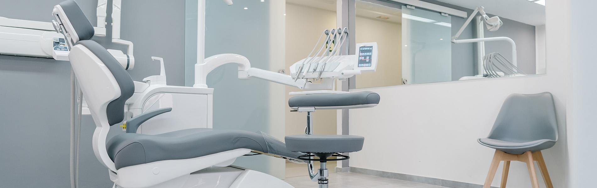 The image shows a modern dental clinic interior with various pieces of equipment, including a dental chair and an X-ray machine.